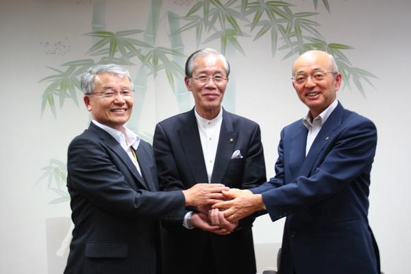 長岡京市長と男性1名、市長が手を重ね合わせ記念撮影している写真